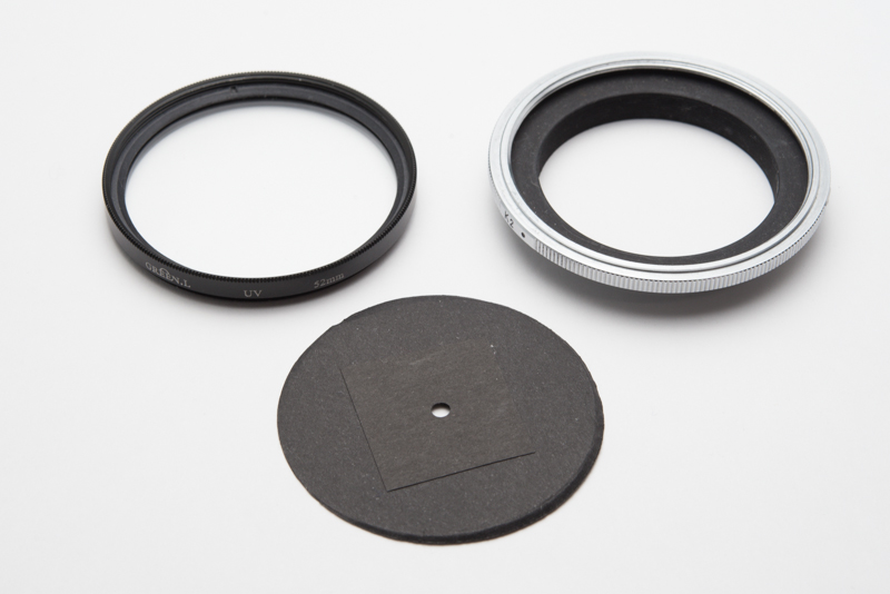 穴をカメラに付けるための部品。左上：52mmのフィルター。レンズ保護用のものやUVフィルターなど。右上：ニコンの接写リング。この製品は現在発売されていない、各カメラ向けのリバースアダプターリングを使うといい。下：黒い紙に3mm径の穴を空けたもの。