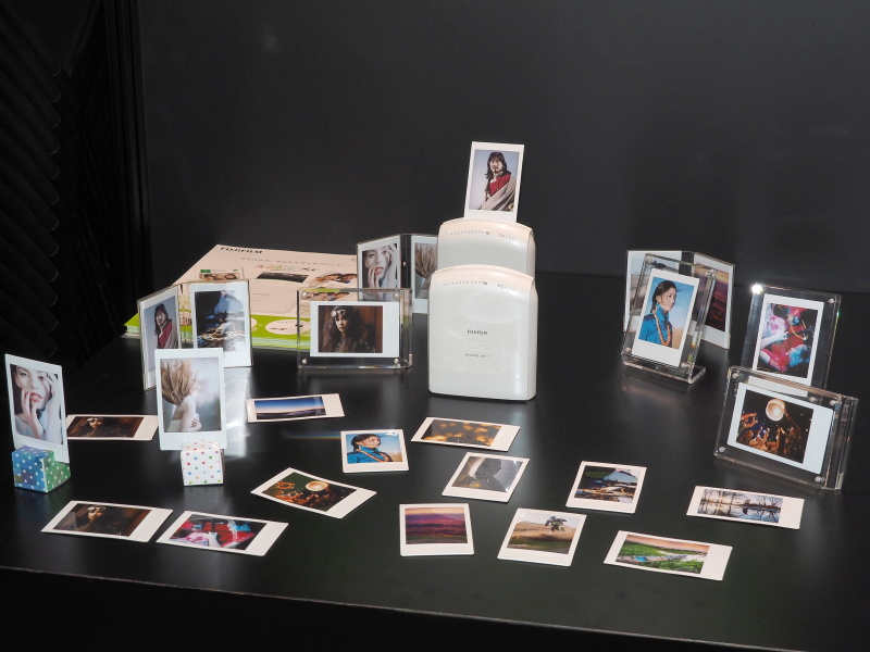 会場にはスマホ画像をチェキのインスタントフィルムにプリントできる「instax SHARE SP-1」の姿も。ファームアップでXシリーズ機から直接プリントできるようにする計画があるという。