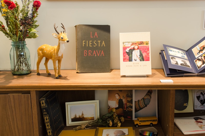 黒板の下には、自宅のリビングのようなムードを醸し出す木目調の棚。写真や小物の飾り方の参考になります。