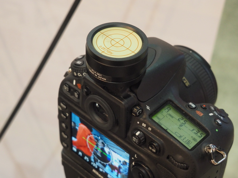 カメラ用精密水準器PLV-001の装着例。0.25度の傾きも計測できるというのが特徴。蓄光機能により、数秒間ライトで照らすとしばらく発光する。本体はアルミ削り出し