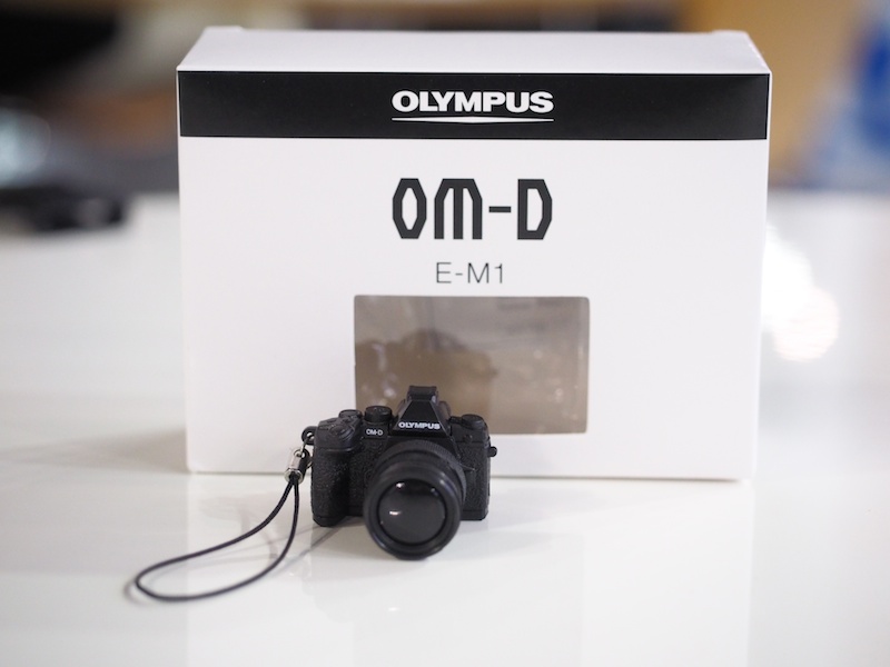 オリンパスブース。オリンパス製カメラを持ってオリンパスブース受付に行くと、「E-M1ミニチュアカメラが付いたオリジナル携帯ストラップ－非売品－」がもらえます。※1人1個まで。なくなり次第終了。