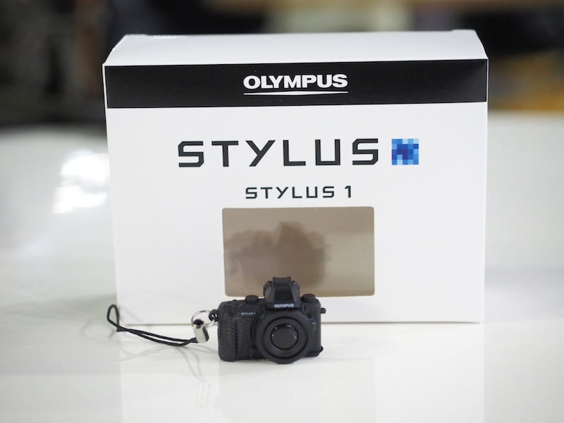 スマートフォンアプリ「OLYMPUS Image Share」をダウンロードして、Wireless（OI.Share）コーナーに行くと「STYLUS1ミニチュアカメラが付いたオリジナル携帯ストラップ－非売品－」がもらえます。※1人1個まで。なくなり次第終了。
