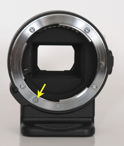 マウントアダプターFT1のレンズ側（左）とボディ側（右）。ボディ側は電子マウントなので接点のみだが、レンズ側には絞り制御用のレバーがある。レンズ側のマウント面のAFカップリングに相当する場所には孔を塞いだ跡がある（矢印）。