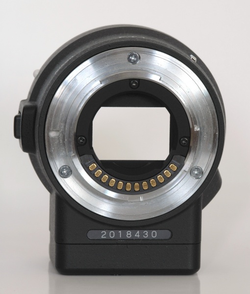 マウントアダプターFT1のレンズ側（左）とボディ側（右）。ボディ側は電子マウントなので接点のみだが、レンズ側には絞り制御用のレバーがある。レンズ側のマウント面のAFカップリングに相当する場所には孔を塞いだ跡がある（矢印）。