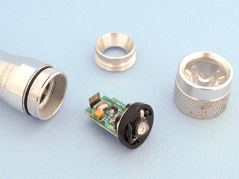 GENTOS PATRIOPRO GT-10AAの先端パーツを外すと、電子回路と一体になったLEDライトが摘出できる。これは電圧を高める昇圧回路で、そのおかげで電池2本（3V）で高照度LEDの発光を可能にしているのだ。