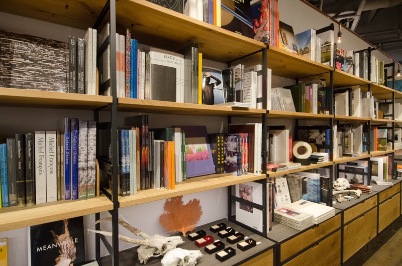 壁に沿って並んだ本棚にも写真集がたくさん。写真を飾るための小物やインテリア雑貨なども販売しています。