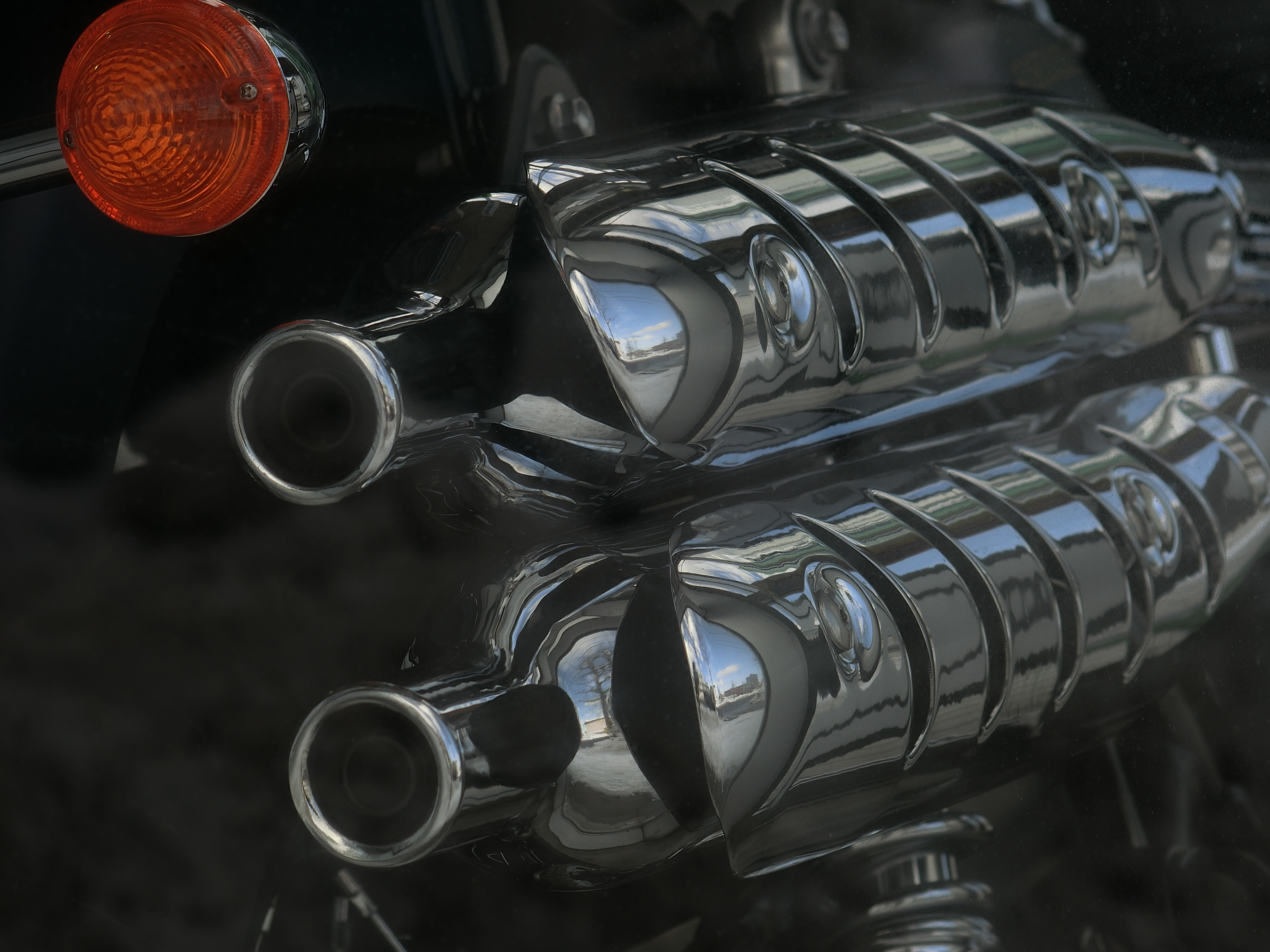 バイクのマフラーを200mm相当で。ガラス越しなので少し写り込みがあるのと、解像力もちょっと落ちてるはず。ISO80 / F4 / 1/400秒 / 42.5mm（200mm相当）