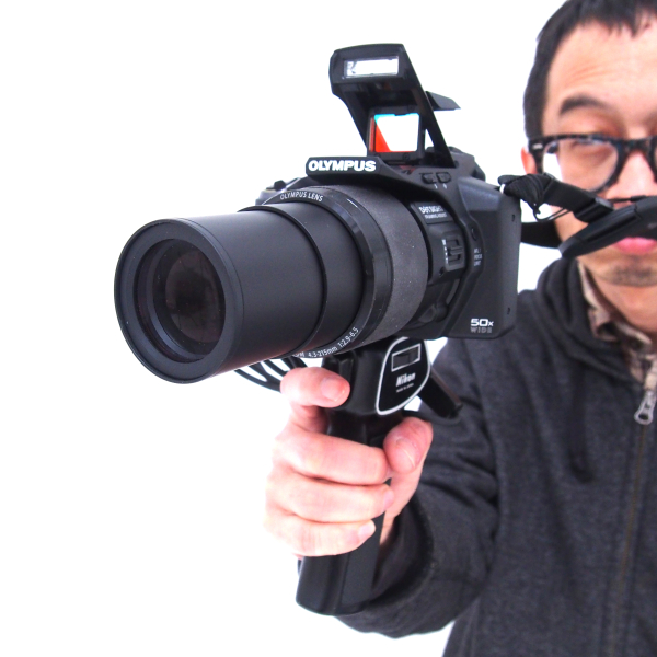 まさに「撃つ!」という感じで気分も高揚するが、傍目にはちょっとアブナイかもしれない（笑）。しかし、このようにグリップを握り、ストラップをピンと張った状態で構えると、安定性も増してなかなか使い勝手が良い。ドットサイトはこのように目を離しても不思議とよく見えるし、この状態で背面液晶モニターと組み合わせると、より簡単に構図決定ができる。