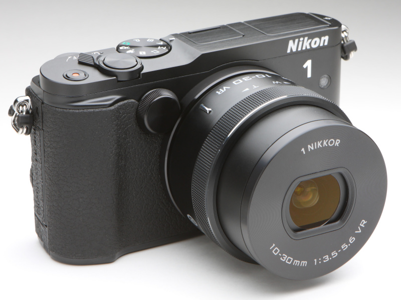 EVFが無くなりフラットになったトップカバー、控えめなグリップ、前面部のアクセントとなっているサブコマンドダイヤルなど先代Nikon 1 V2とは大きく異なるボディシェイプを持つ。