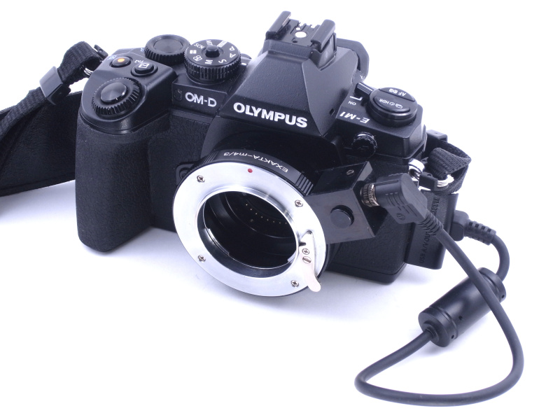 「自動絞りマウントアダプター」をオリンパスE-M1に装着したところ。コードの一端はカメラ本体のUSB端子に接続する
