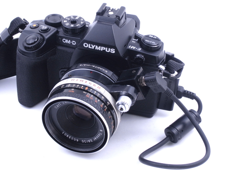 テッサー50mm F2.8を装着したところ。レンズの絞り込みボタンと、マウントアダプターのシャッターボタンとが重なり「外部連動自動絞り」が実現する。左手側にUSB端子があってちょっと邪魔だが、もともとエクサクタは使いにくいカメラなので、あまり気にならない（笑）