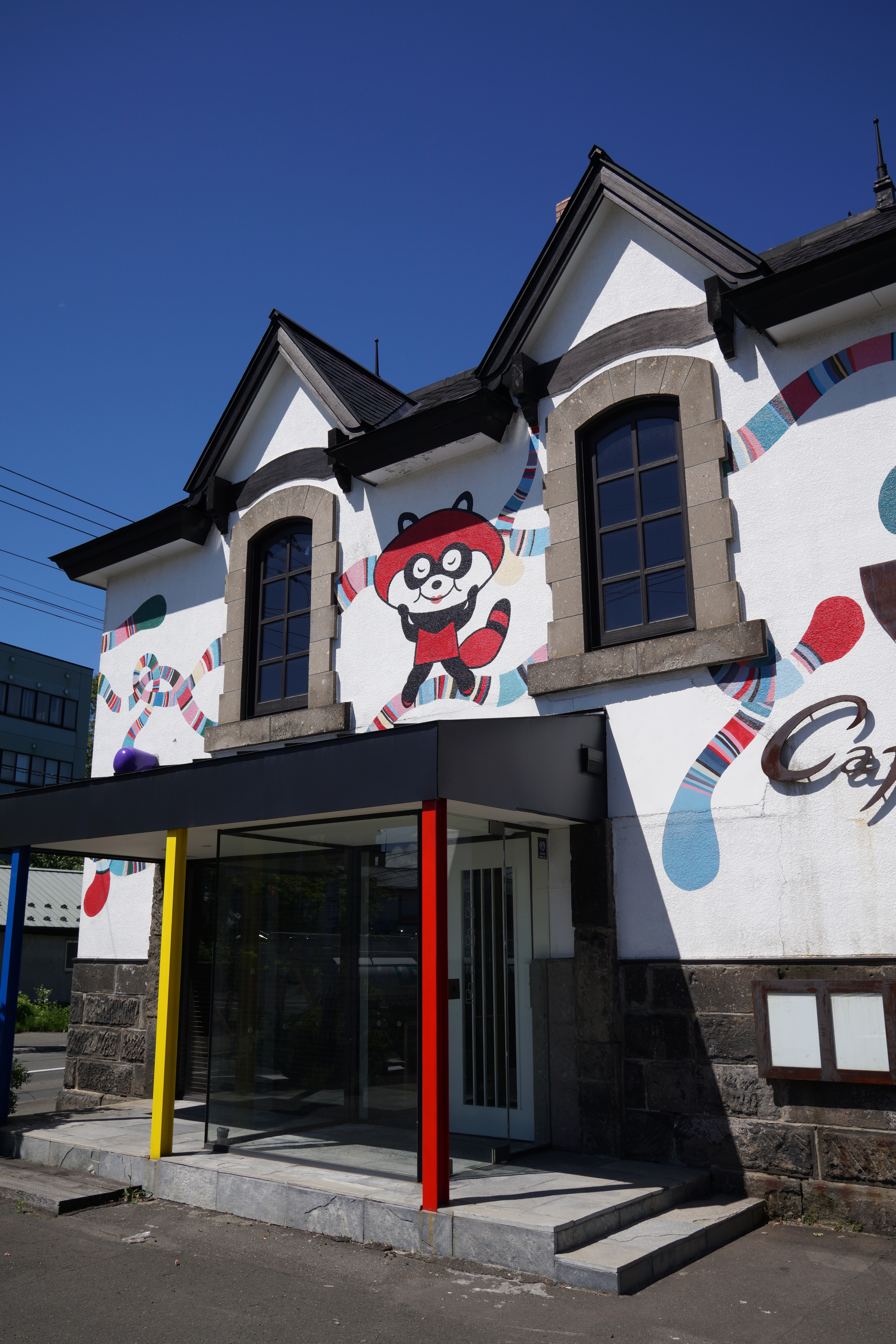 石蔵を改装したカフェらしい建物。壁の画のポップさに目を引かれた。19mm F2.8 DN / 1/800秒 / F6.3 / ISO100 / 絞り優先AE / 19mm