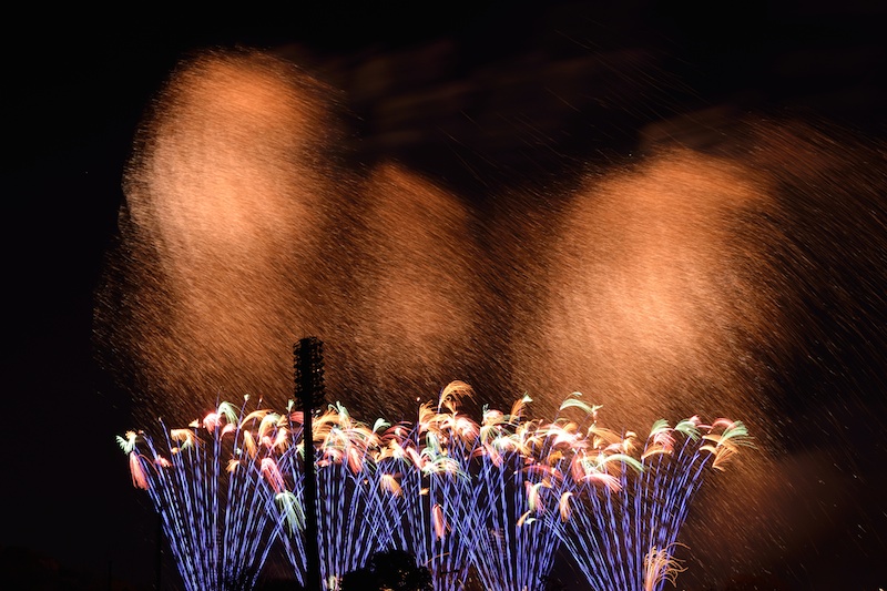 スターマインの一場面で和火の柳が何発も開花した。柳はゆっくりと垂れ下がってくるタイプの花火だ。低空の噴出花火は青色でしかも先端が小さな彩色の柳だった。D600・AF-S NIKKOR 18-35mm f/3.5-4.5G ED・マニュアル露出・F5.6・3.8秒・WB:AUTO2（電球色を残す）・ISO100・ND4フィルター・リモートケーブル・三脚