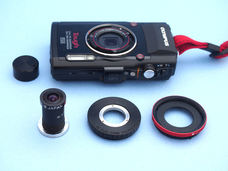 現在、魚露目8号にはデジカメのフィルターネジに取り付ける専用アダプターが用意されている（前中）。今回はTG-3専用コンバーターアダプター（前右）に合わせ、40.5mm径タイプをセレクトした。ちなみに左奥に置かれたのは魚露目8号専用レンズキャップで、同じネットショップで入手できる