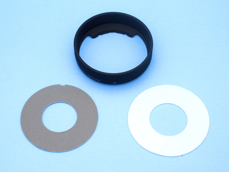 レンズフードLH4-01を、リングストロボに転用するためのパーツを製作。左はレンズ取り付け座で、イラストボードをサークルカッターでカットして製作。右はストロボ光拡散板で100円ショップで買ったプラスティックのトレイ（半透明乳白色）を同じくサークルカッターでカットして製作した