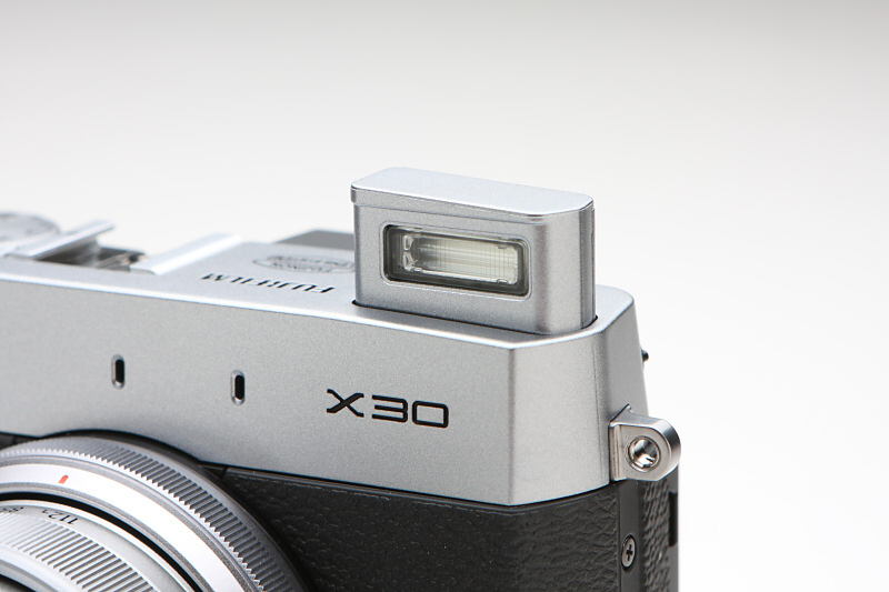 手動ポップアップ式のフラッシュを内蔵。ISO800の際の撮影可能範囲は、ワイド端で0.3mから7mまで、テレ端で0.5mから5mまでとする