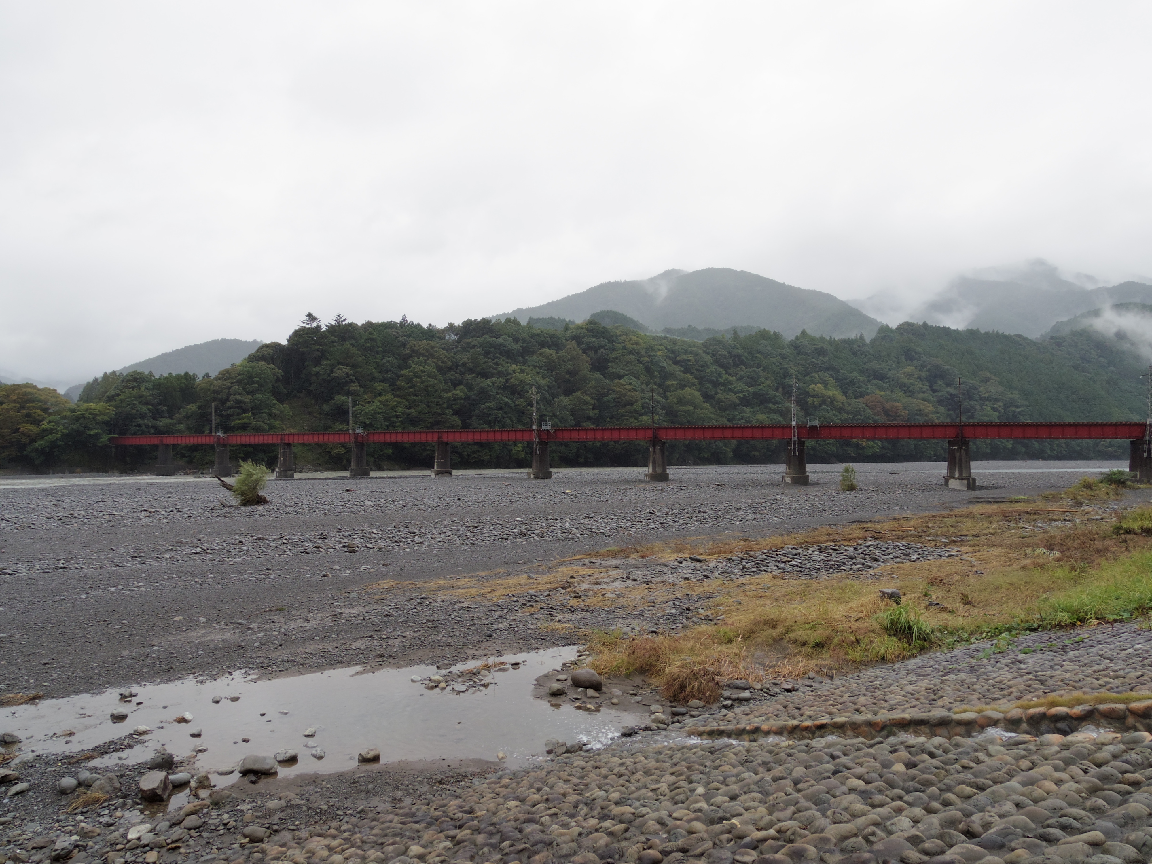 小雨の降る中、大井川鉄道の陸橋を臨む家山駅近辺より撮影。山の向こう側は白く煙っています。ISO200 / F4.5 / 1/125秒 / ±0EV / 5mm（23mm相当）
