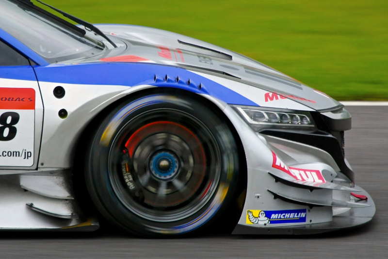 撮影者コメント：「タイヤとの会話」スプーン入口でのブレーキングでは凄まじい減速エネルギーにより真っ赤に焼けるブレーキローターと、それを受け止めるフロントタイヤ。キヤノンEOS 40D / 1/800秒 / F6.3 / ISO100 / 400mm