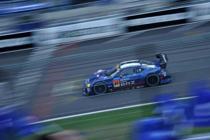 撮影者コメント：レース終盤、スバルファンシートの前を駆け抜けるBRZと応援フラッグを絡めて撮影しました。ニコンD700 / 1/60秒 / F5.3 / ISO360 / 66mm