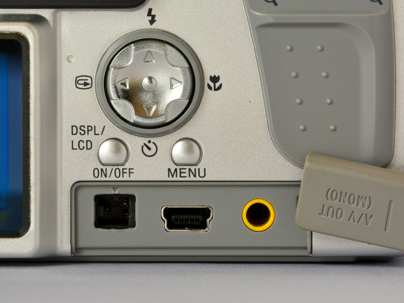 背面部下のカバー内には、DC IN端子、USB端子、AV/OUT端子、と並ぶ（左から）。ボディ形状の関係もあると思うけど、端子の位置が側面じゃなくて背面とは、ちょっと珍しいかも。