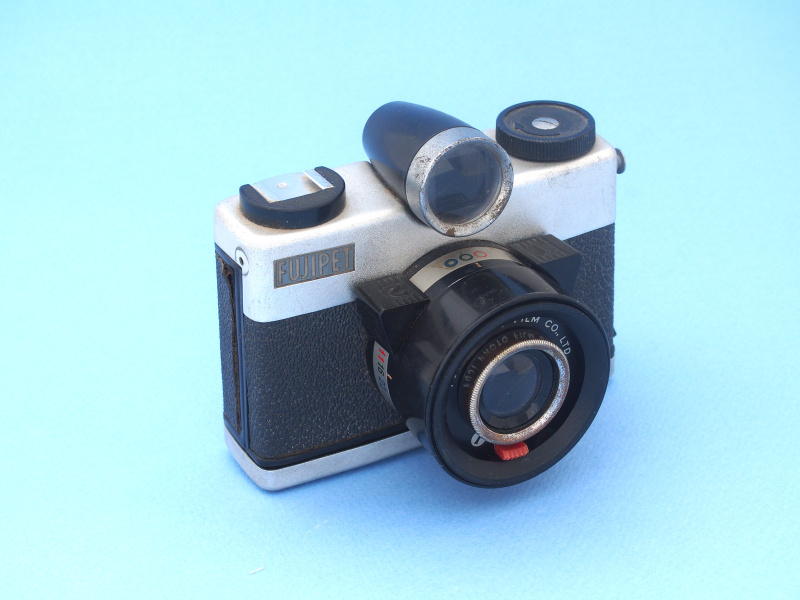 フジペットは富士フイルムが子どもへの需要拡大を狙い1957年に発売した、安価でシンプルなカメラだ。○▽□を基調としたデザインはいま見ても秀逸で、メーカーの意気込みが表れている。操作は向かって右の三角レバーでシャッターセットし、左の三角レバーでシャッターを切る。シャッターは1/50秒の単速で、絞りF11～22で露出調節する。ピント合わせ不要の固定焦点である