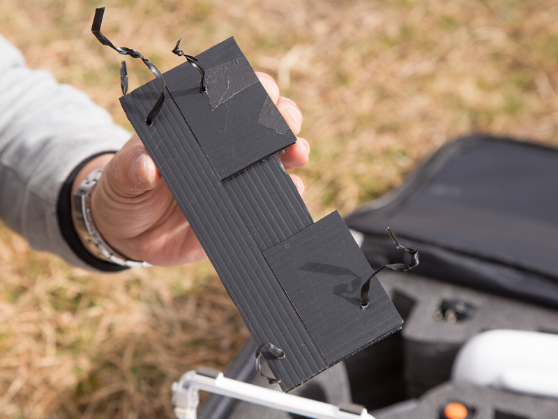 スキッドの隙間に合わせて、プラスチック段ボールを切り出し、巻き付け用の針金を通したところ。穴あけにドライバーかキリを使う