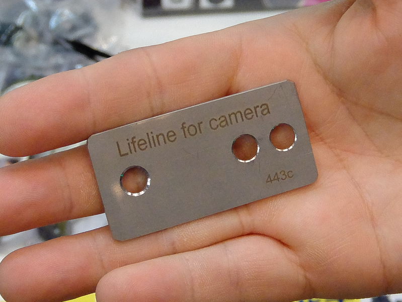 左の穴を三脚ネジに通し、右側の穴に紐を結ぶ