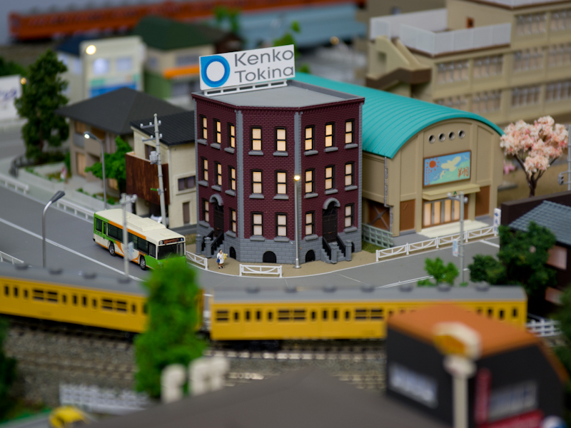 フィルター試し撮りコーナーには鉄道模型が走る。現本社のKT中野ビルを模した建物もあった