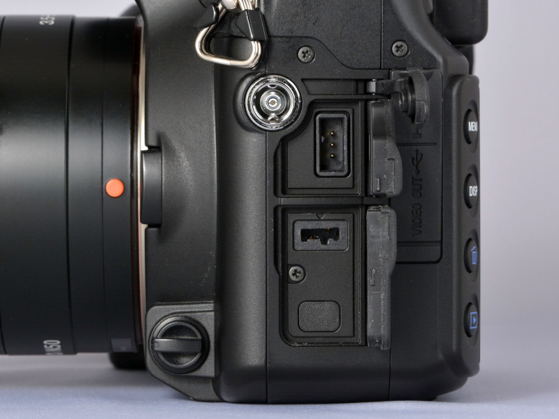 側面部カバー内に、各種の接点が配置されている。前列には、シンクロターミナル、REMOTE端子、DC IN端子。後列（ここではカバーを閉じた状態）には、HDMI端子、VIDEO OUT/USB端子、と並ぶ。