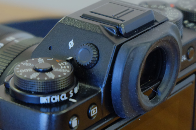 ファインダー横に付いている視度調整ダイヤルを回しながら、ファインダー内の表示（例えば数字など）がクリアに見えるように調整します。