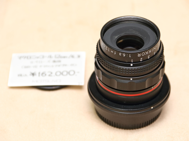 <strong class="">ニコンMacro-Nikkor 12cm F6.3</strong><br class="">ベローズ専用のマクロレンズである。恐らくは産業用だったと思われる。ベローズに装着すると無限遠がでるため、アイデア次第では様々な撮影で楽しめそうだ。写真のアイテムにはFマウントアダプターBR-15が付属。（カメラのアルプス堂）