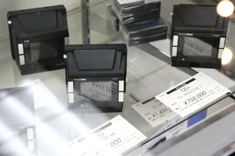 フェーズワンのデジタルバックがいくつも並ぶショーケース。まだまた高価だが、それでも新品の半値以下だ。このようなアイテムが見られるのも中古カメラ市の魅力。（フォトベルゼ）