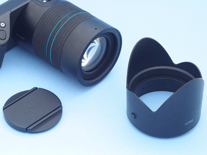 ちなみに付属レンズフードは、一般的なバヨネットとは異なる装着方式を採用している（フード側面のスイッチを押し、レンズ先端にフード内側のピンをはめ込む）。レンズキャップは一般的な中つまみ式だが、デザインが独創的でしゃれている。ストラップ取り付け金具も凝っている。とにかくこのカメラは細部にわたり“これまでに無いカメラ”を目指して作られているのがわかって面白い