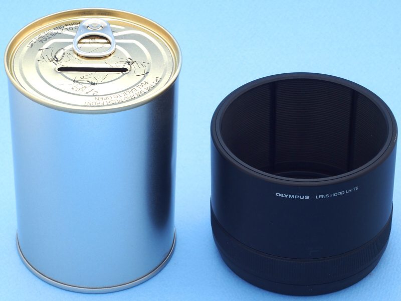 ところでM.ZUIKO DIGITAL ED 40-150mm F2.8 PROには引き出し機能を備えた優れたフードが付属している（右）。ところが中古で買ったCarl Zeiss Jena 180mm f2.8にはフードが無い。このレンズは単層コーティングということもあり、有害光をカットするフードは必需品だ。そこで100円ショップで買った「貯金缶」（左）を素材に、レンズフードを自作することにした
