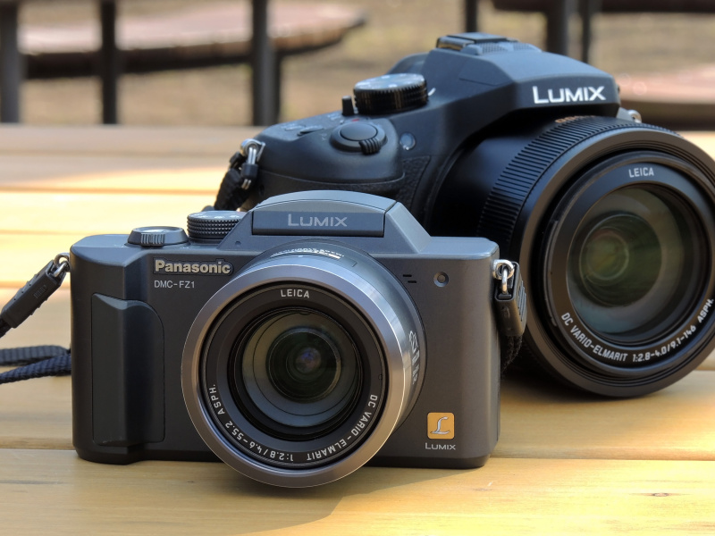 パナソニックLUMIX DMC-FZ1。2002年から現在まで続くFZシリーズは、この1台から始まった。後ろに従えているのは、現行（シリーズ最新）の1型センサー搭載モデル「LUMIX DMC-FZ1000」。こうやって近くに置いてみると、LUMIX DMC-FZ1のコンパクトさが際立つ。