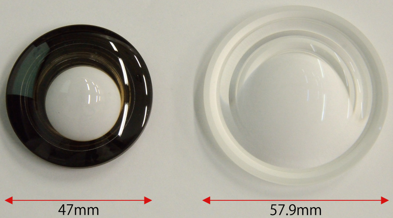 <strong class="">大型化できたガラスモールド非球面レンズ</strong><br class="">生産技術向上＆新しい成形技術の開発により、従来（直径47mm/写真左）よりも大型のガラスモールド両面非球面レンズ（XGMレンズ/直径57.9mm/写真右）の量産が可能となり、このレンズの高い画質性能を実現できた