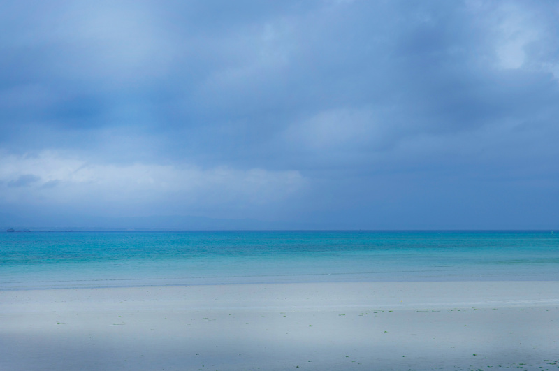 沖縄のエメラルドグリーンの海。ブルーの雲から浜辺にかけてのグラデーションが美しい。<br class="">・着眼点：海、空、浜辺のグラデーション<br class="">・撮り頃：色が正しく出る日中<br class="">・イメージ：ひと気ない海の静けさ<br class="">・撮影テクニック：3要素のほどよい配分<br class="">・ひと工夫：アクセントは地平線のみ<br class="">100mm相当 / シャッター優先オート / F8 / 1/500秒 / ISO100 / WB：太陽光