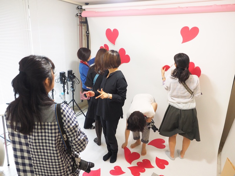 撮影は5名ずつの2グループに分かれて行われました。1グループが撮影している間に、もう1グループが次のシチュエーションのセッティング。チームワークはバッチリです。白いバック紙だと味気ないので、ハートを貼ってかわいくデコレーション。