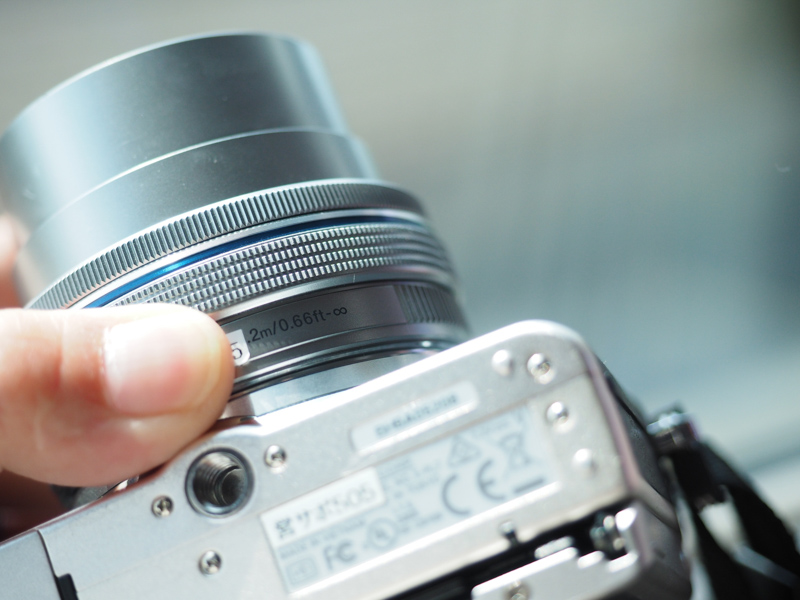 レンズに書かれた「●m/●ft-∞」という数値が最短撮影距離です。E-PL7のキットレンズM.ZUIKO DIGITAL ED 14-42mm F3.5-5.6 EZは0.2m（0.66ft）まで寄ることができます。