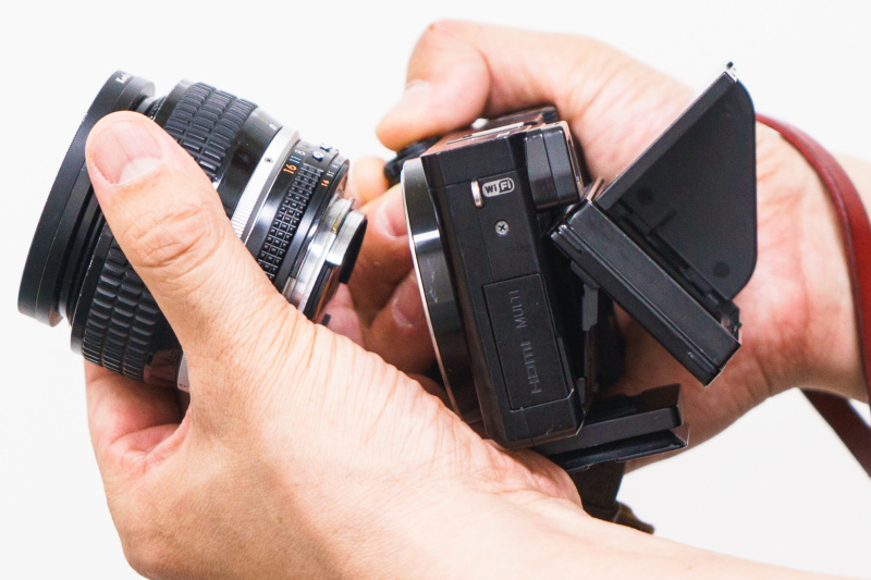 カメラにぶつけないようレンズ上端の位置を指で支えて、レンズの下側を上に持ち上げる