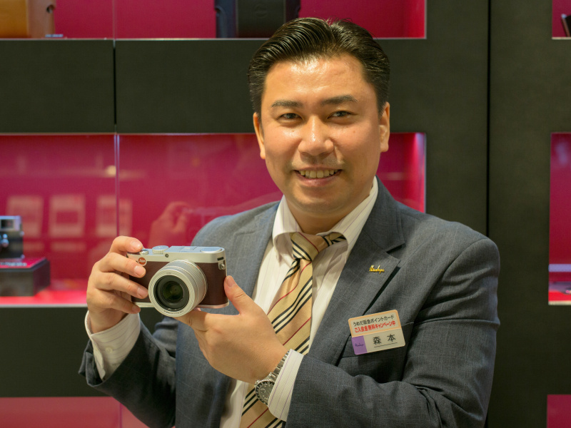 ライカ阪急うめだ店の森本朗巨店長。オープン記念の「ライカXマルーン」を手に