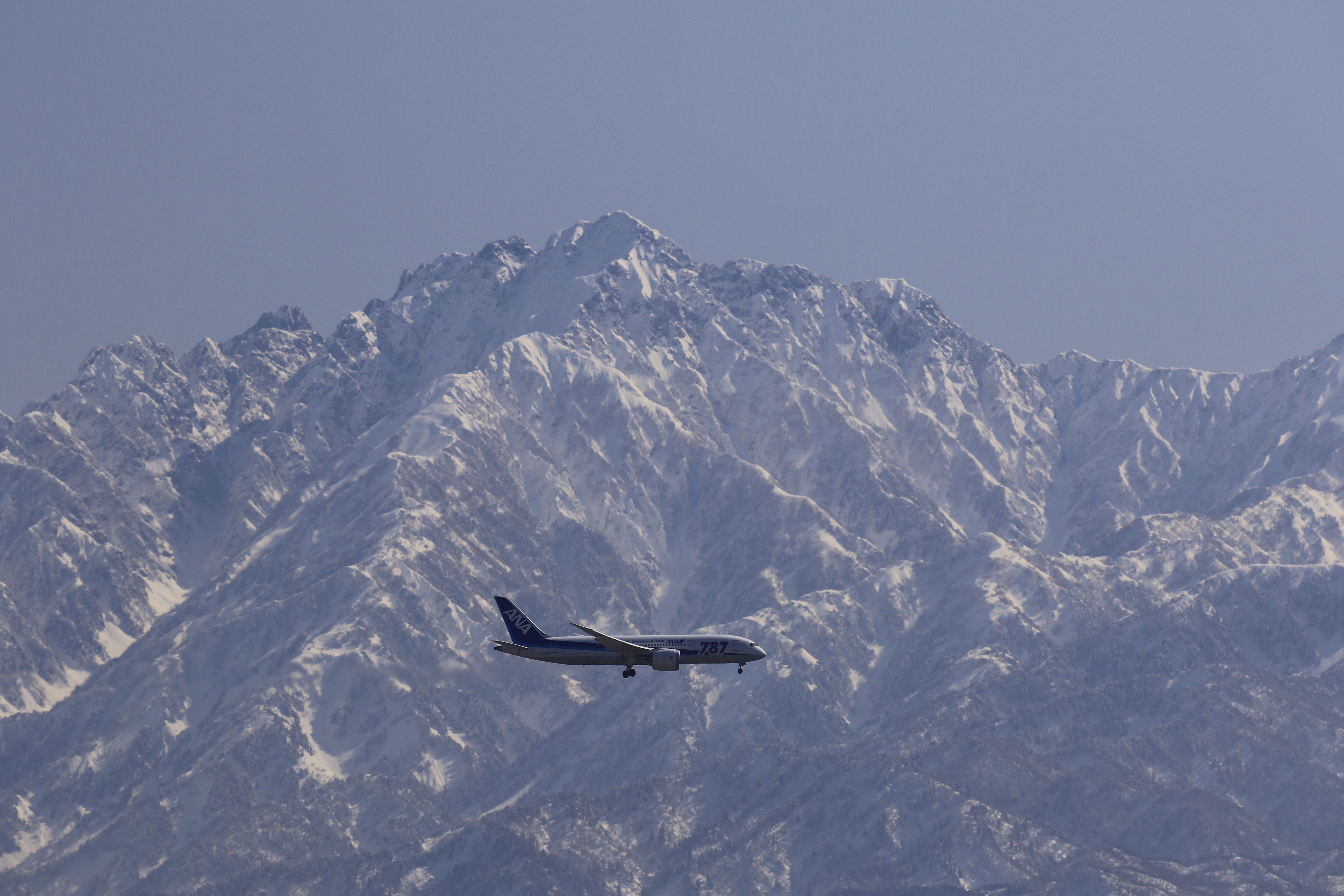 雪をたたえる山脈をバックに飛ぶ飛行機も、100-400mmという広いズーム域なら、風景を入れたり、山の稜線に合わせて撮影するなど、ファインダー上でさまざまにトリミングができる。このカットがイメージ通りの出来となった。<br>キヤノン EOS 7D Mark II / EF100-400mm F4.5-5.6L IS II USM / 255mm（408mm相当） / 絞り優先AE（F6.3、1/1,600秒、-0.3EV）/ ISO 250