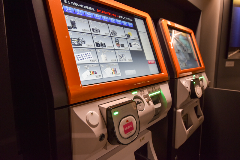 ニコンオリジナルグッズはタッチパネル端末で購入できる。引換券が出たらインフォメーションカウンターに持っていく。