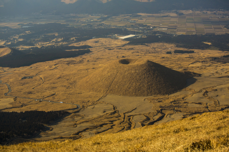 <strong class="">【要素が多いと主役が弱まる】</strong>メインカットより広い75mmで撮影すると、街やバスなど具体的な被写体が写り込み、米塚の面白さが半減する