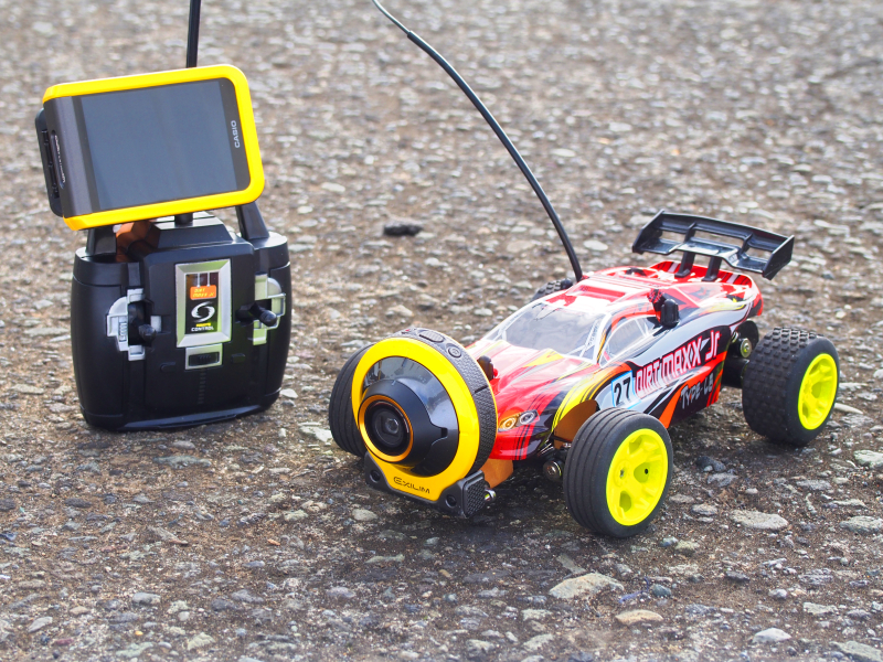 ラジコンカーの先端にカシオ「EXILIM EX-FR100」を装着。ラジコンのコントローラにもFR100のコントローラを装着しているから、モニターで映像を見ながらラジコンカーが操作できる。昨今はドローンによる空撮が流行っているが、その「逆」の発想をしてみたのだが、地上スレスレのネズミのような視点から、疾走するラジコンの迫力ある動画を撮ることができる