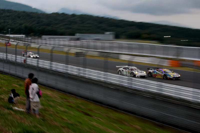 まいくらさん。「看板背負って」世界を代表するスポーツカーメーカーどうしのクラス2位を懸けた意地の張り合い。6時間レースも残り15分を切った。コカコーラ進入のスピード感を、ズームの流しで表現してみました