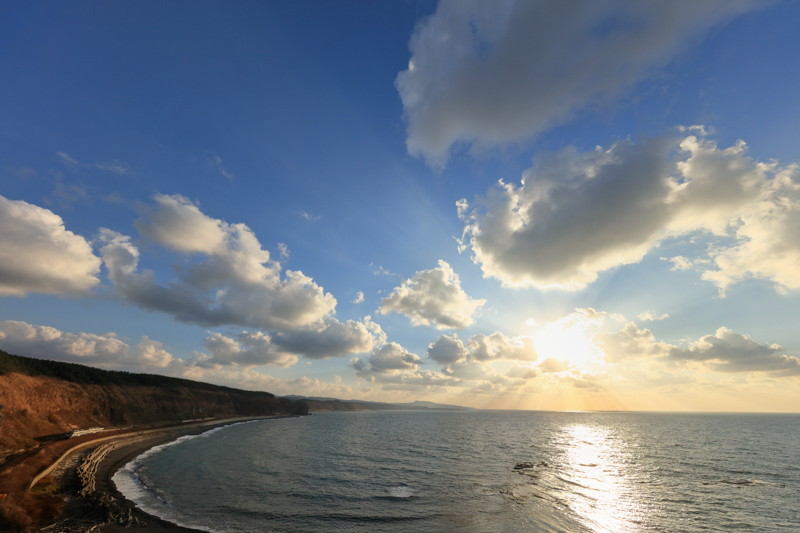 青森県と秋田県の日本海に沿うようにして走る五能線。夕日の美しい路線として人気がある。超広角なので列車が小さくなってしまうが、その存在感を出さなければ鉄道写真と言えない。車体がギラリと光る瞬間を狙った。EOS 5Dsは秒間約5コマの連写性能があるのでベストな瞬間を捉えられる。<br><span class="fnt-85">キヤノン EOS 5Ds / EF11-24mm F4L USM / 11mm / マニュアル露出（F8、1/800秒） / ISO 400</span>