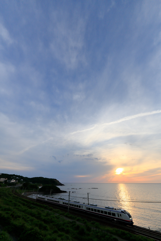 日本海の夕暮れと特急「しらゆき」。私が注目したのは夕日ではなく雲の表情。少しでもダイナミックに取り入れたい願いは、広い画角が叶えてくれた。超広角かつ速度の速い特急列車。高速シャッターが必須であり、それはブレ防止にもつながる。<br><span class="fnt-85">キヤノン EOS 5Ds / EF11-24mm F4L USM / 13mm / マニュアル露出（F5、1/1,600秒） / ISO 800</span>