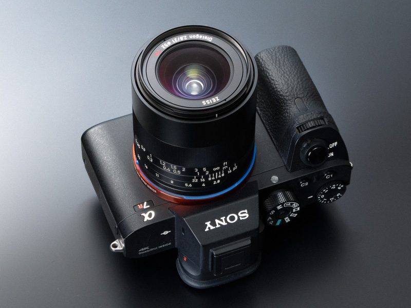α7R IIとの組み合わせは、形状や質感、ホールドバランスの面でうまくマッチしている。デザイン的には、ソニーのシナバー（朱色）にツァイスの青という主張の強い色の組み合わせが面白い