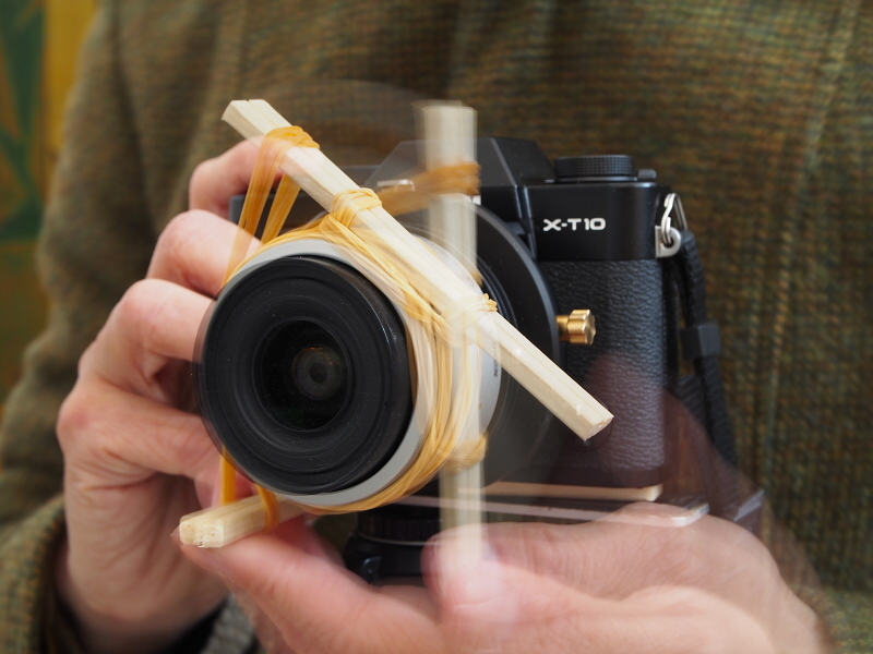 このようにレバーを引いてゴムの力をチャージし、シャッターボタンを押すのと同時にレバーを離すと「瞬間露光間ズーム」が可能になる……はずなのだが、実際に試してみるとタイミングが非常に難しい。そもそもこの「装置」を付けたままでは、レンズそのものをシフトする事ができなくなり、もう1つのアイデアがスポイルされてしまう